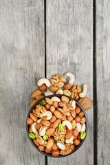 Wooden bowl with mixed nuts on a wooden gray background. Walnut, pistachios, almonds, hazelnuts and cashews, walnut.