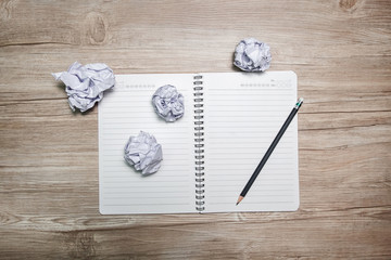 Crumpled paper ball and notebook on a black background.
