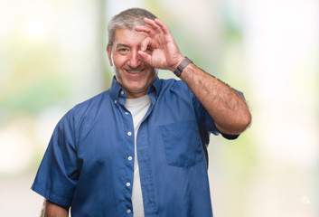 Handsome senior man over isolated background doing ok gesture with hand smiling, eye looking through fingers with happy face.