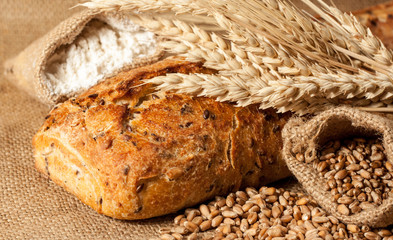 Retro bread in rustic style background.Fresh traditional bread on wooden ground with flour in a sack.