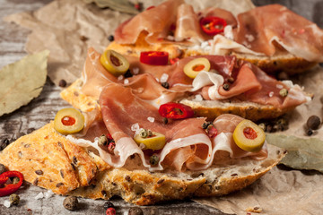 Bruschetta with roasted bell pepper, prosciutto, garlic, olives, spices and herbs. Appetizers.