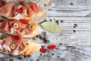 Bruschetta with roasted bell pepper, prosciutto, garlic, olives, spices and herbs. Appetizers.