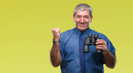 Handsome senior man looking through binoculars over isolated background screaming proud and celebrating victory and success very excited, cheering emotion