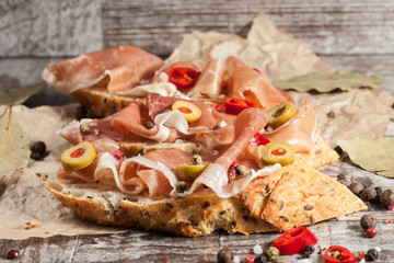 Bruschetta with roasted bell pepper, prosciutto, garlic, olives, spices and herbs. Appetizers.