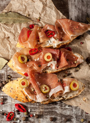 Bruschetta with roasted bell pepper, prosciutto, garlic, olives, spices and herbs. Appetizers.