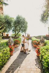 young beautiful couple girl in white dress man in white shirt stand in the garden at sunset in summer