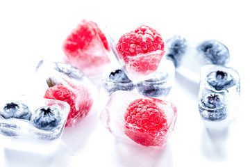 frozen blueberry and raspberry in ice cubes on white background