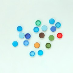 many plastic caps of different colors on light background. Concept of recycling plastic. Square