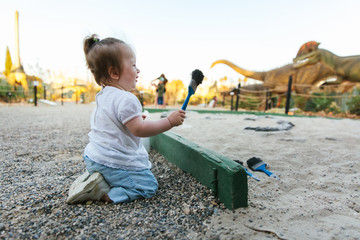 White girl have fun digging in the sand at adventure park, selective focus