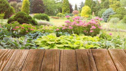 Wooden table and blurred view of beautiful garden on background. Space for text