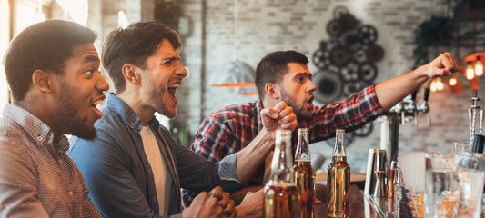 Diverse friends watching football game in bar