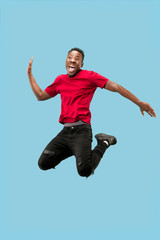 Freedom in moving and forward motion. The happy surprised young african man jumping a against blue studio background. Runnin man in motion or movement. Human emotions and facial expressions