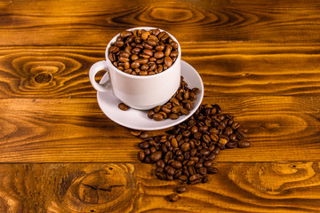 White cup filled with coffee beans on wooden table