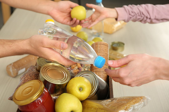 Volunteers Taking Food Out Of Donation Box On Table, Closeup