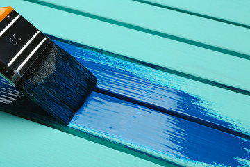 Brush and blue paint stroke on wooden background, closeup. Space for text