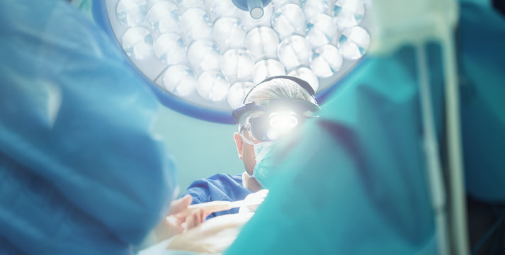 surgeon with lights doing open heart cardiac surgery in hospital cardiovascular microsurgery with minithoracotomy procedure, surgeon operating beating heart surgery with his medical team