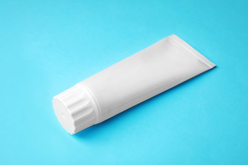 Blank tube of toothpaste on color background