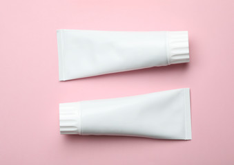 Blank tubes of toothpaste on color background, top view