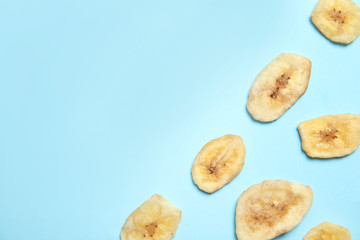 Flat lay composition with banana slices on color background, space for text. Dried fruit as healthy snack