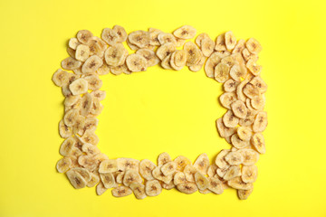 Frame made of sweet banana slices on color background, top view with space for text. Dried fruit as healthy snack