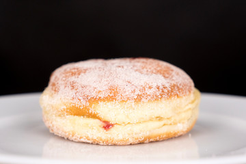 Berliner Pfannkuchen auf weißem Teller vor schwarzem Hintergrund