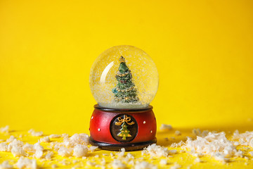 Snow globe with Christmas tree on color background