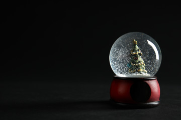 Snow globe with Christmas tree on dark background. Space for text