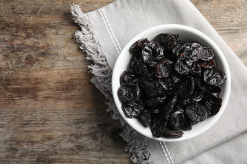 Bowl of sweet dried plums on table, top view with space for text. Healthy fruit