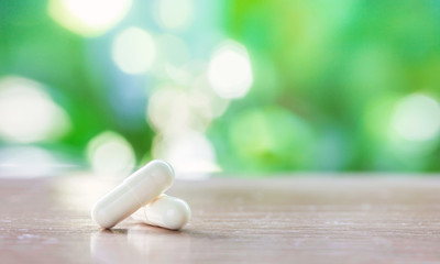 white medicine capsule on wooden table with natural background