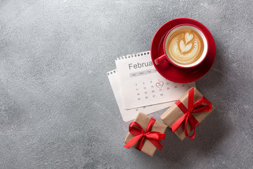 Valentines day greeting card. Red coffee cup and gift box over february calendar. Top view