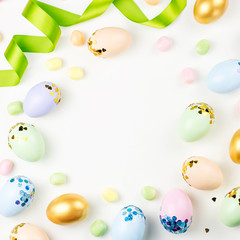 Festive Easter background with decorated eggs, flowers, candy and ribbons in pastel colors on white. Copy space