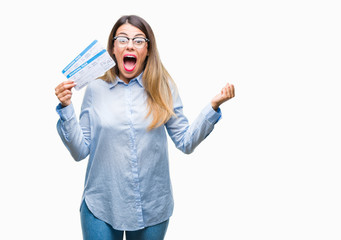 Obraz premium Young beautiful woman holding boarding pass over isolated background very happy and excited, winner expression celebrating victory screaming with big smile and raised hands