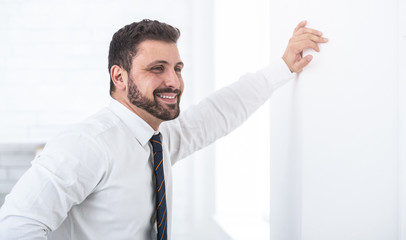 Happy businessman leaning on the wall staring ahead © Prostock-studio