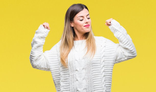 Young beautiful woman casual white sweater over isolated background showing arms muscles smiling proud. Fitness concept.