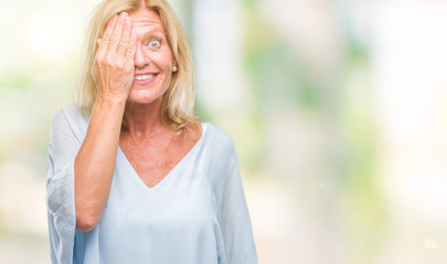Middle age blonde business woman over isolated background covering one eye with hand with confident smile on face and surprise emotion.