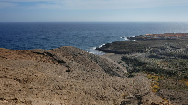 Elevated views from Pelada Mountain, or Montana Pelada, an arid volcanic cone, towards the small wild beach and the arid coastal landscape that surrounds it, in Tenerife, Canary Islands, Spain