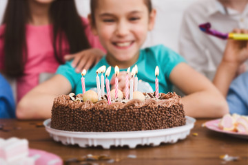 Adorable girl celebrating birthday and blowing candles on cake