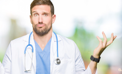Handsome doctor man wearing medical uniform over isolated background clueless and confused...
