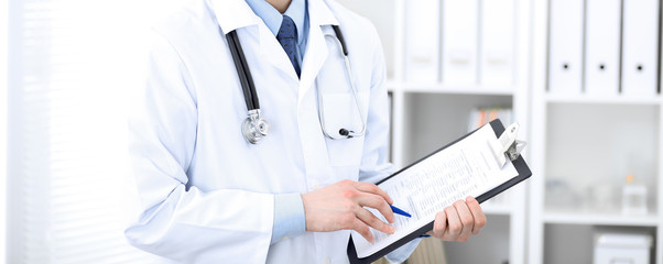 Male doctor standing upright with crossed arms, unknown physician at work. Medicine concept