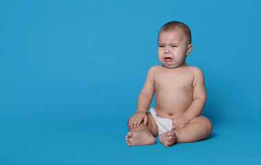 Crying baby boy on blue studio background