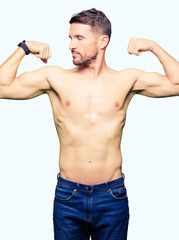 Handsome shirtless man showing nude chest showing arms muscles smiling proud. Fitness concept.