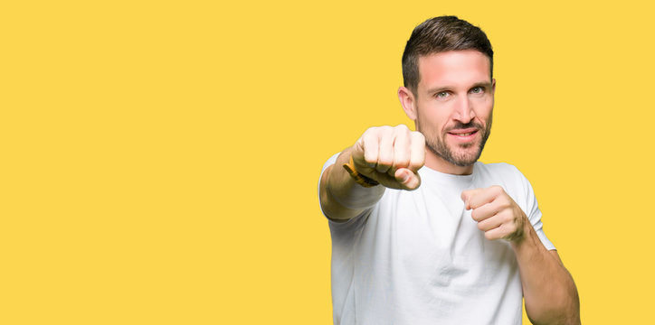 Handsome man wearing casual white t-shirt Punching fist to fight, aggressive and angry attack, threat and violence