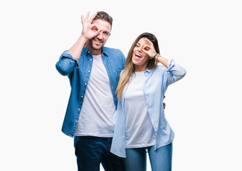 Young couple in love over isolated background doing ok gesture with hand smiling, eye looking through fingers with happy face.