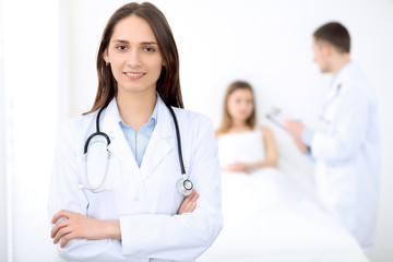 Fototapeta premium Medicine doctor standing and smiling on the background with patient in the bed