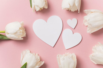 White flowers and hearts on a pastel pink background