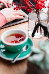 Red tea and man working at his laptop in cafe, green tea, plant, screen, hands.