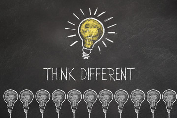 Glühbirnen und Schriftzug "think different" mit eine Idee Glühbirne auf Kreidetafel 