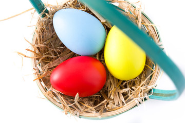 Colorful easter eggs in a basket and tulips isolated on white background. Top view. 