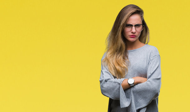 Young beautiful blonde woman wearing glasses over isolated background skeptic and nervous, disapproving expression on face with crossed arms. Negative person.