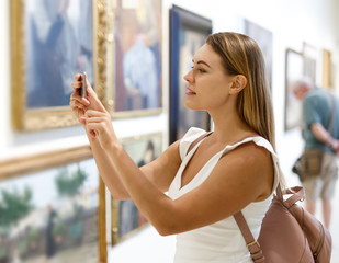 Woman photographing painting in museum